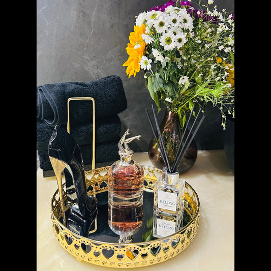 Decorative tray with perfume bottle, flowers, and black high heels on a marble surface.
