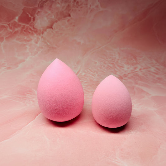 Two pink makeup sponges on a pink textured background