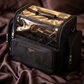 Black travel bag with clear top section on a brown fabric background