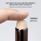 Makeup brush handle with soft bristles, held by a finger, on a light gray background.