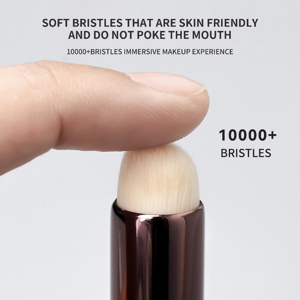 Makeup brush handle with soft bristles, held by a finger, on a light gray background.