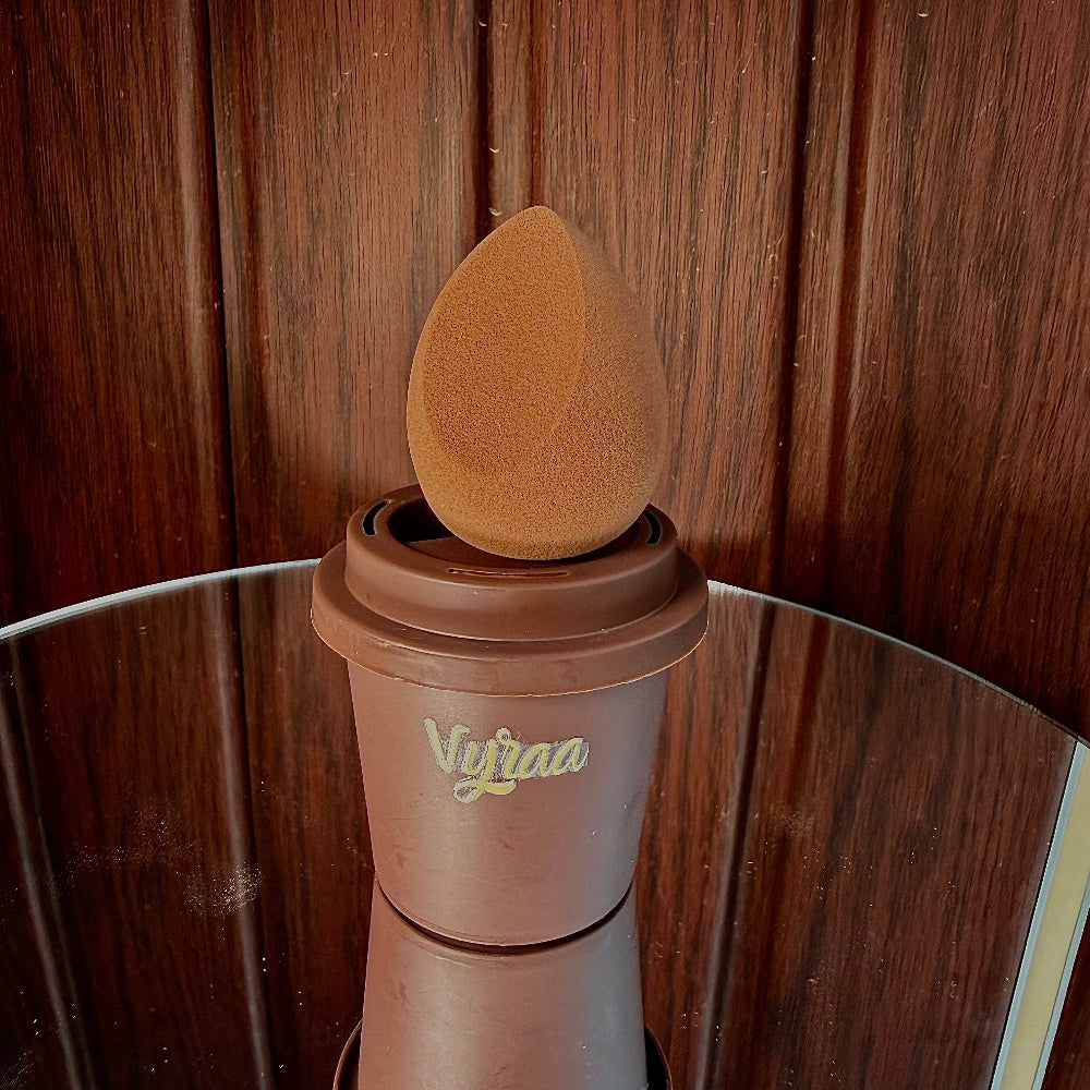 Brown makeup sponge on a stand with 'Vivaaa' branding against a wooden background