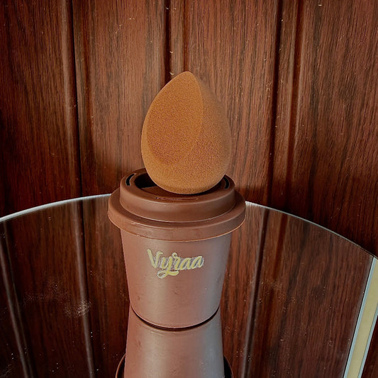 Brown makeup sponge on a stand with 'Vivaaa' branding against a wooden background
