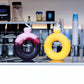 Two colorful drink containers with straws on a counter in a kitchen setting.
