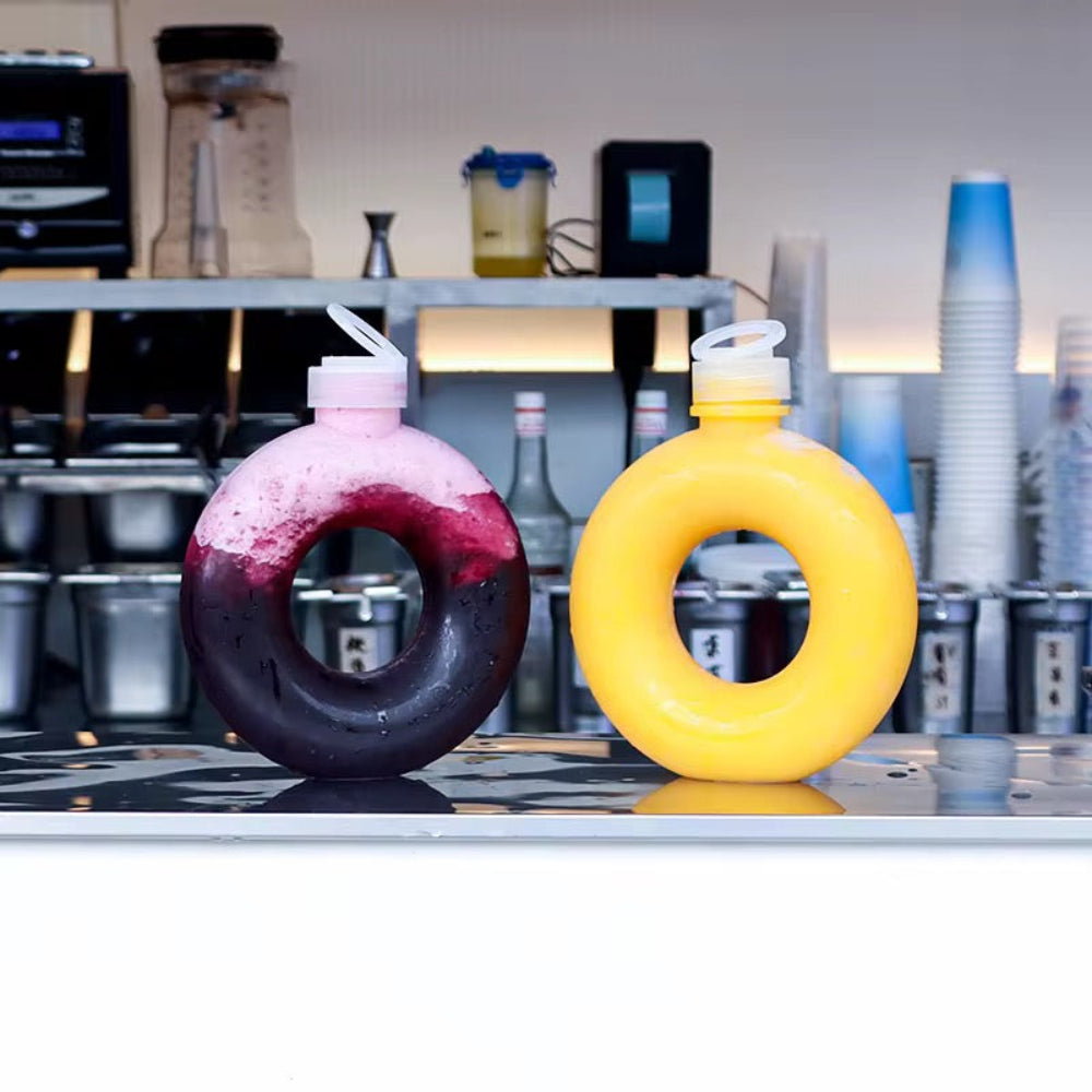 Two colorful drink containers with straws on a counter in a kitchen setting.