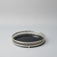 Round decorative tray with intricate border on a light gray background