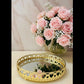 Decorative gold tray with heart designs on a surface with flowers.
