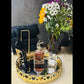 Decorative tray with perfume bottle, flowers, and black high heels on a marble surface.