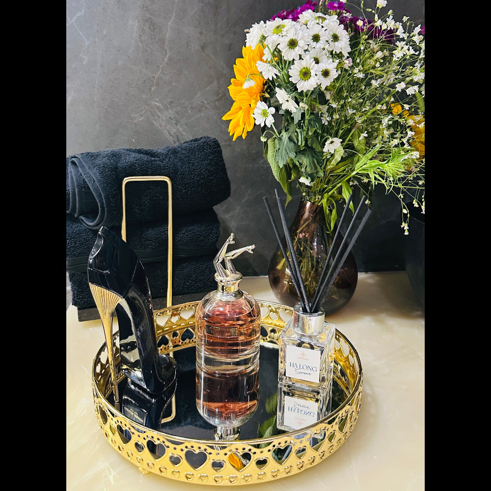 Decorative tray with perfume bottle, flowers, and black high heels on a marble surface.