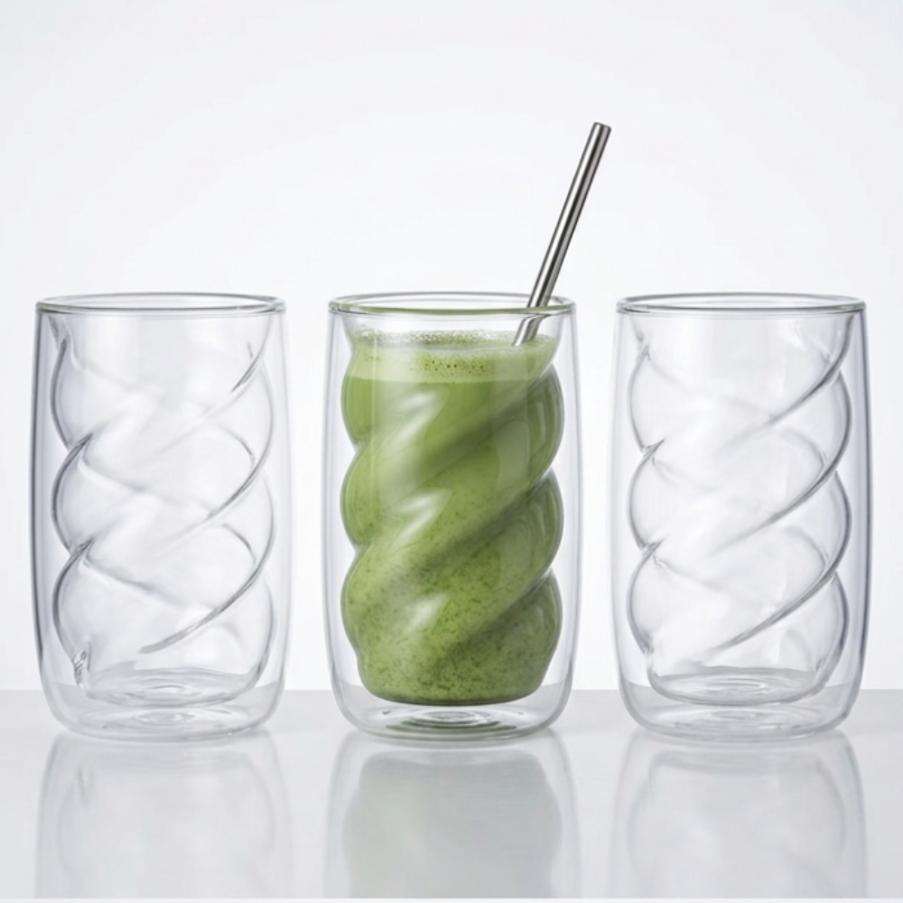 Three glass tumblers with a green smoothie and a metal straw on a white background