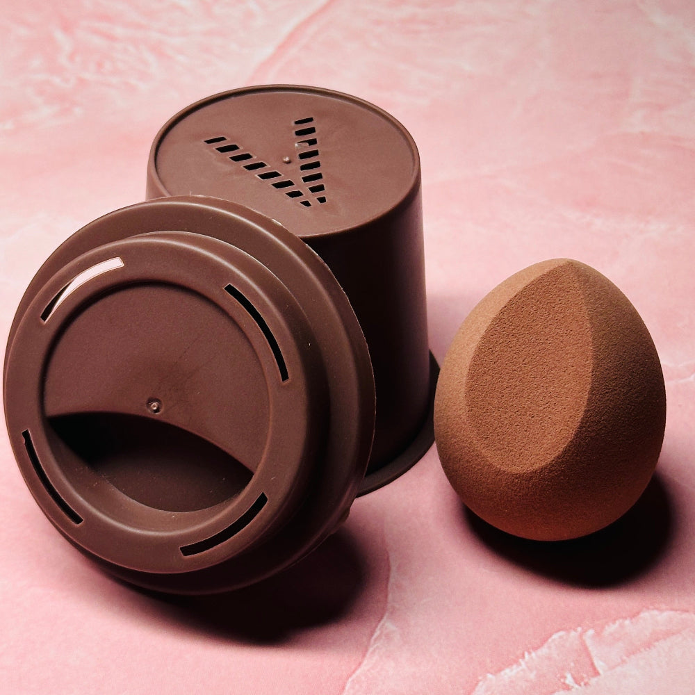 Makeup sponge and container on a pink textured background