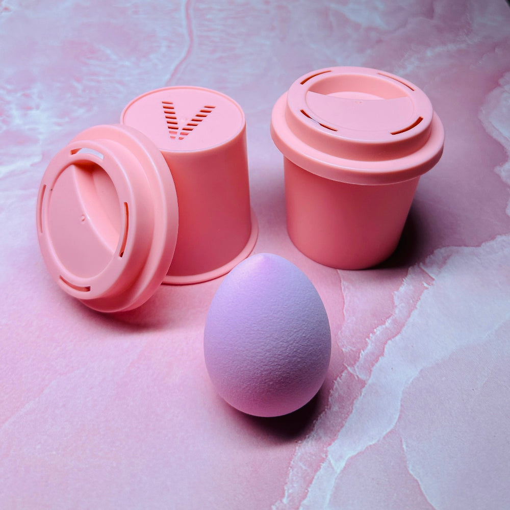 Pink makeup sponges and containers on a textured pink surface