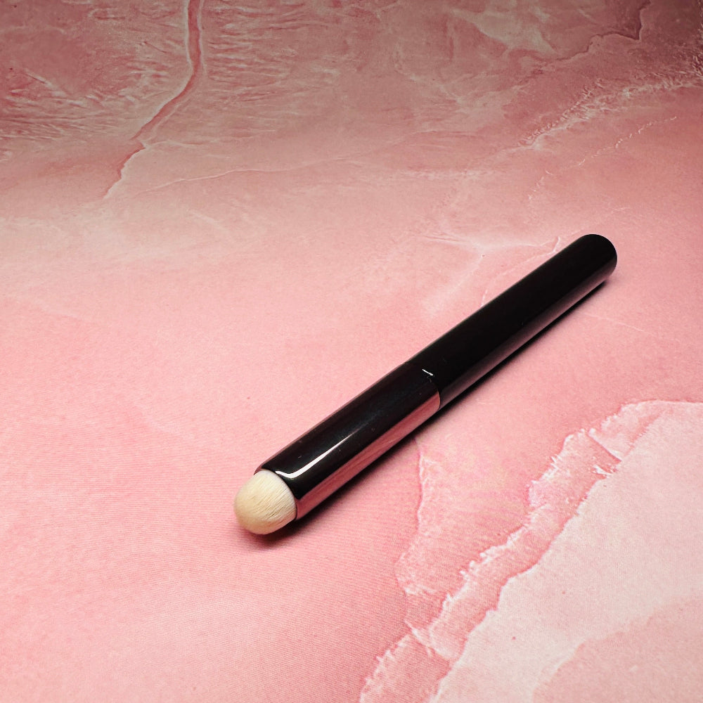 Black makeup brush on a pink textured background