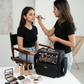 Makeup artist applying makeup to a model with a Vyraa bag and products on a table.